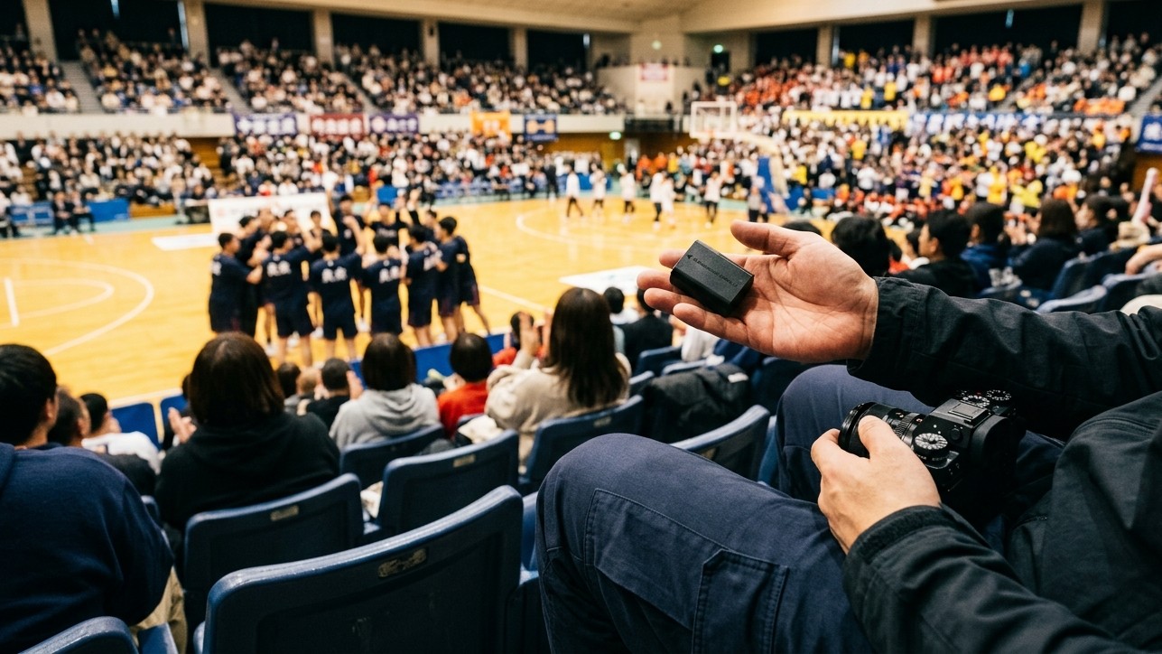 満員の会場で、試合の合間に予備バッテリーを確認している手元