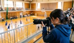 体育館の2階席から望遠レンズで選手を撮影する人
